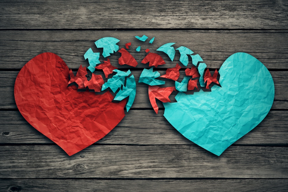 Romantic relationship concept as two hearts made of torn crumpled paper on weathered wood as symbol for romance attachment and exchange of feelings and emotions of love.